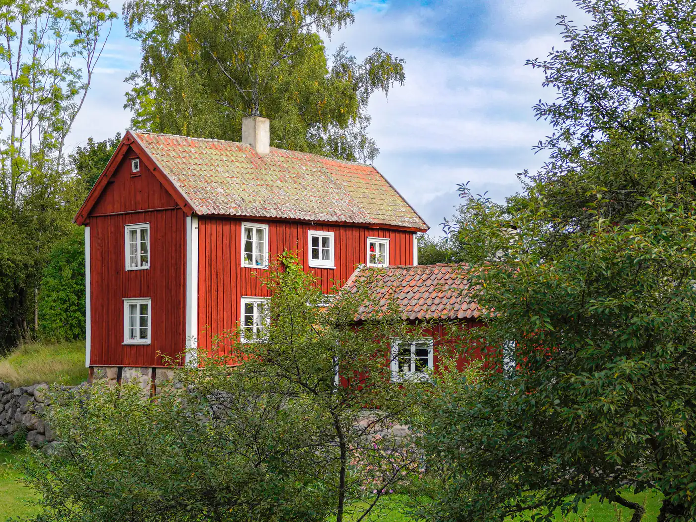 Faluröd träfasad med vita knutar och vita fönster på ett äldre svenskt hus